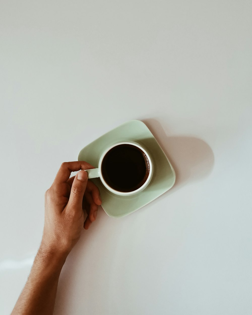 person holding white ceramic mug with black liquid