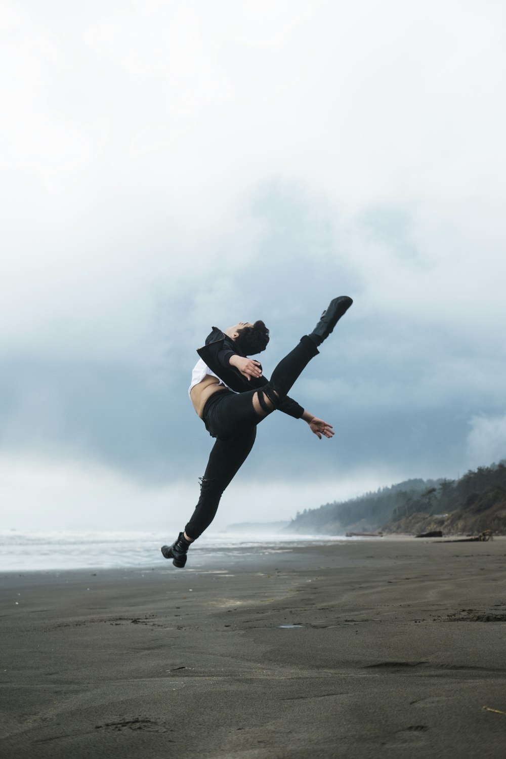 woman in black sports bra and black leggings doing yoga on beach during daytime