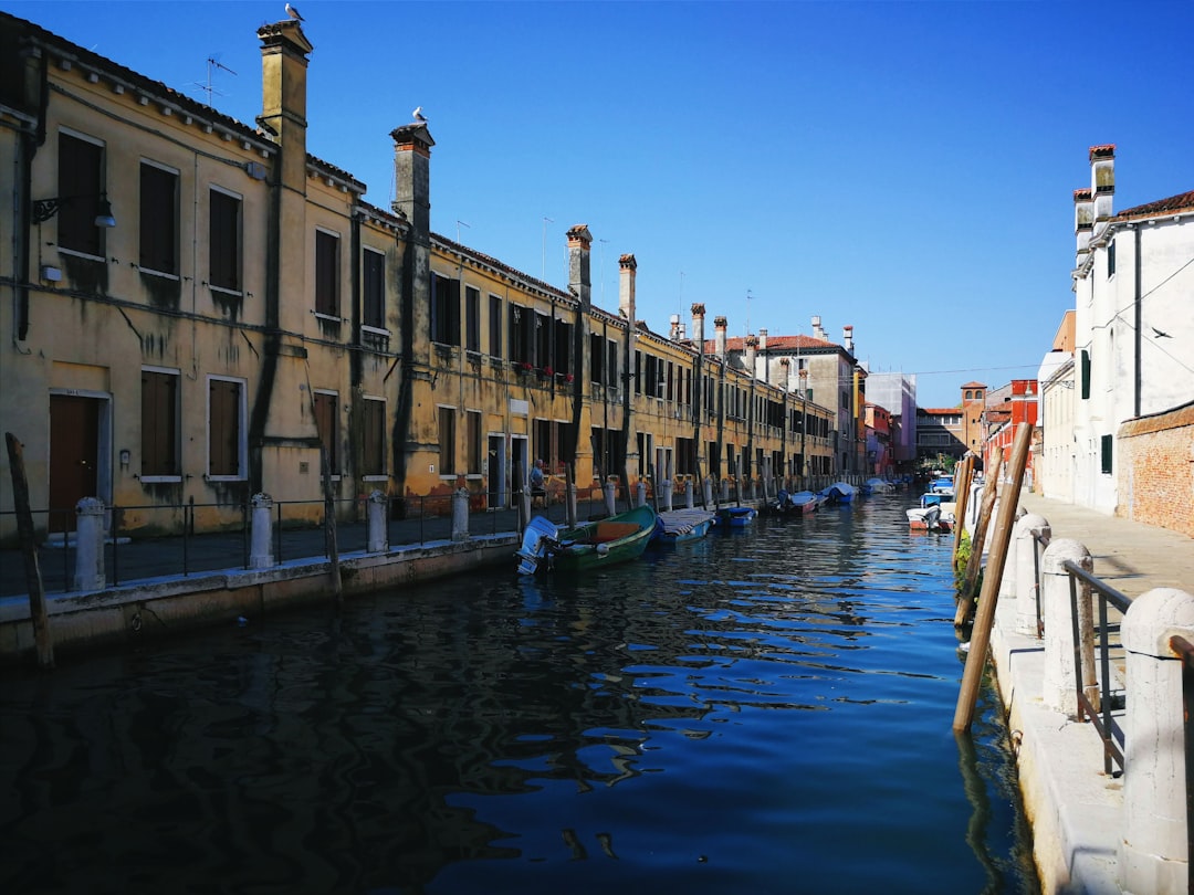 blue boat on water near concrete building during daytime