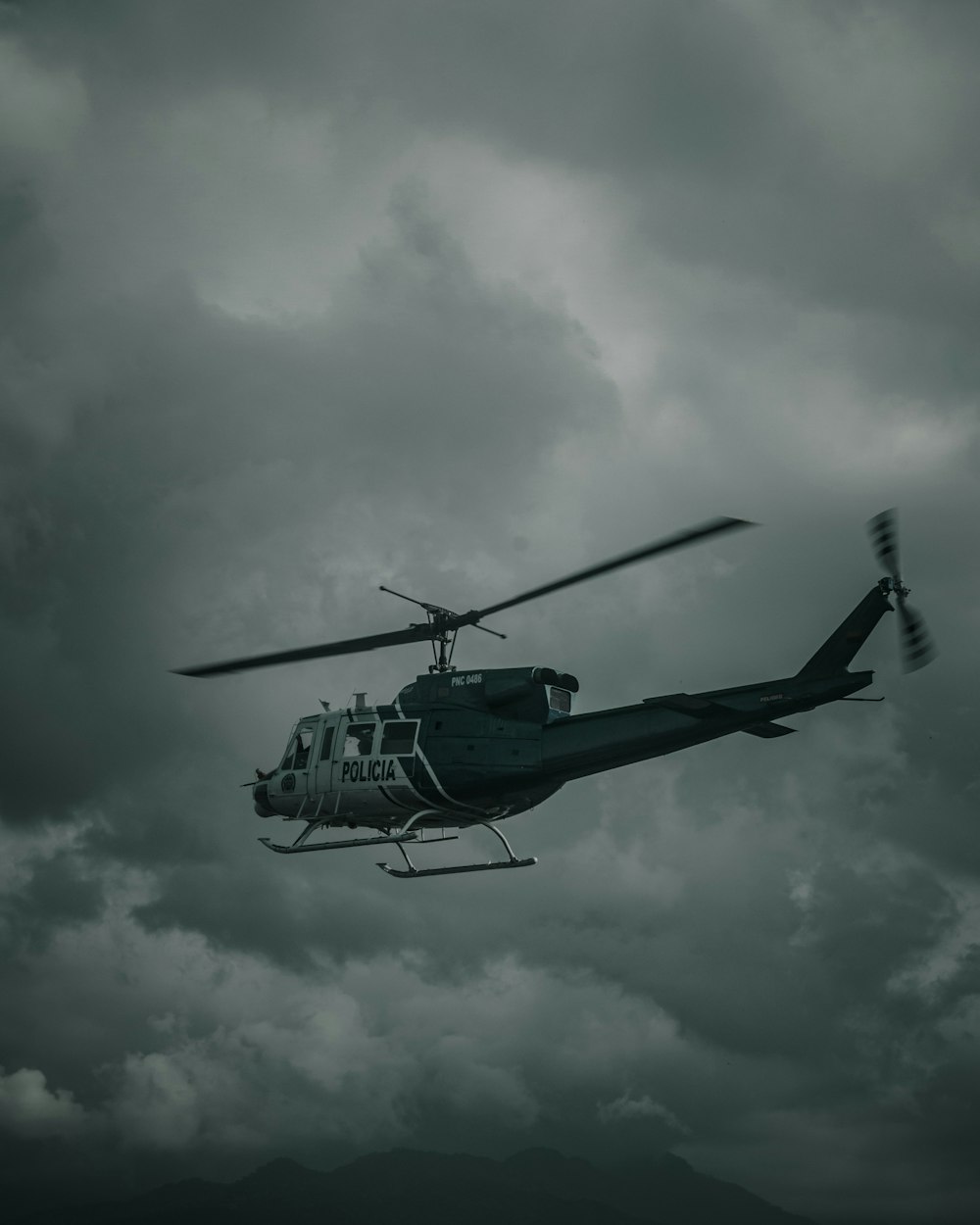 green and black helicopter flying under white clouds during daytime