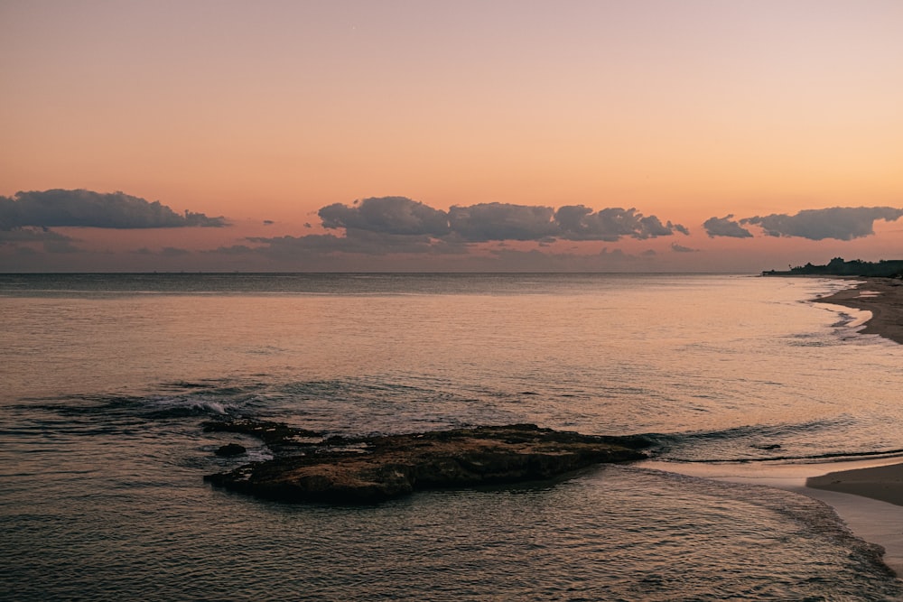 brown rock formation on sea during sunset