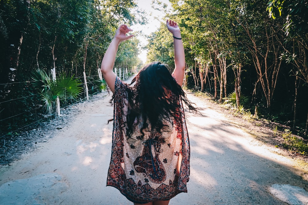 woman in black and brown floral dress standing on dirt road during daytime