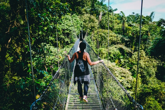 woman in black shirt and black pants standing on hanging bridge