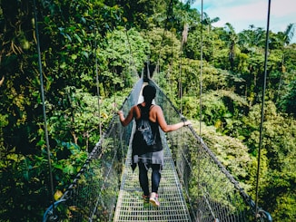 woman in black shirt and black pants standing on hanging bridge