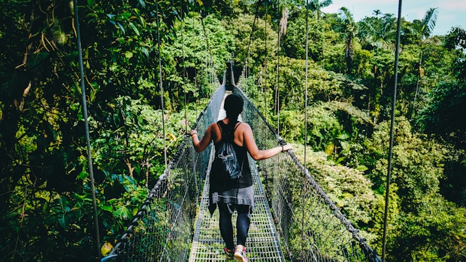 woman in black shirt and black pants standing on hanging bridge