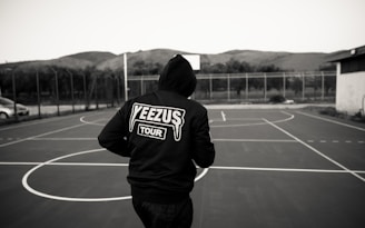 man in black and white hoodie standing on track field