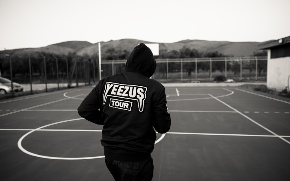 man in black and white hoodie standing on track field