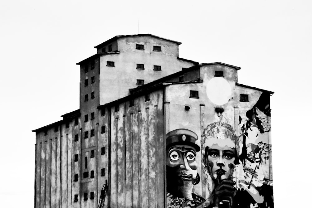 grayscale photo of man in hat and mask on building
