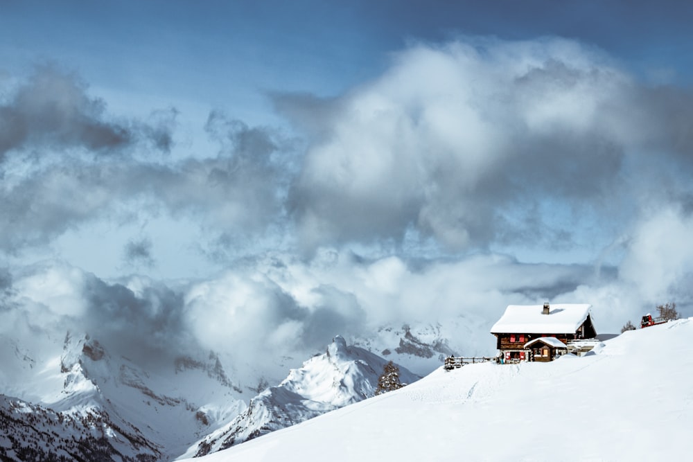昼間は白い雲の下の雪山の上の茶色い家