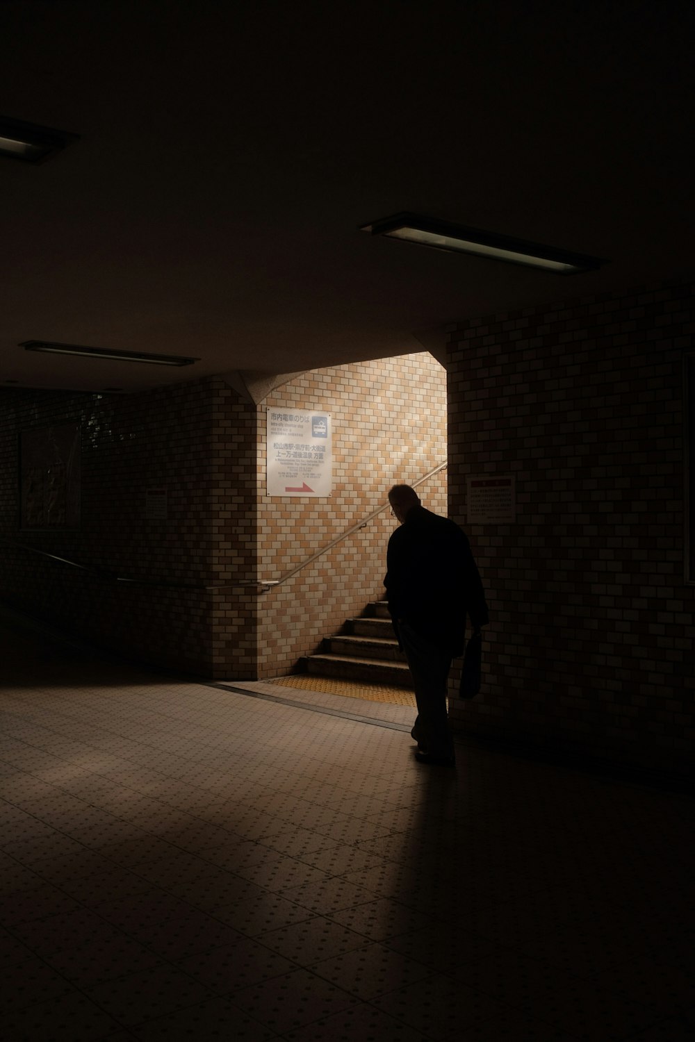 man in black jacket standing near white wall