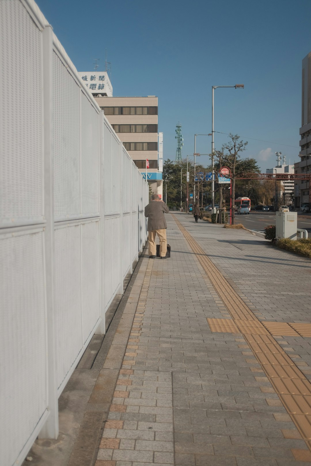 woman in black jacket and brown pants walking on sidewalk during daytime