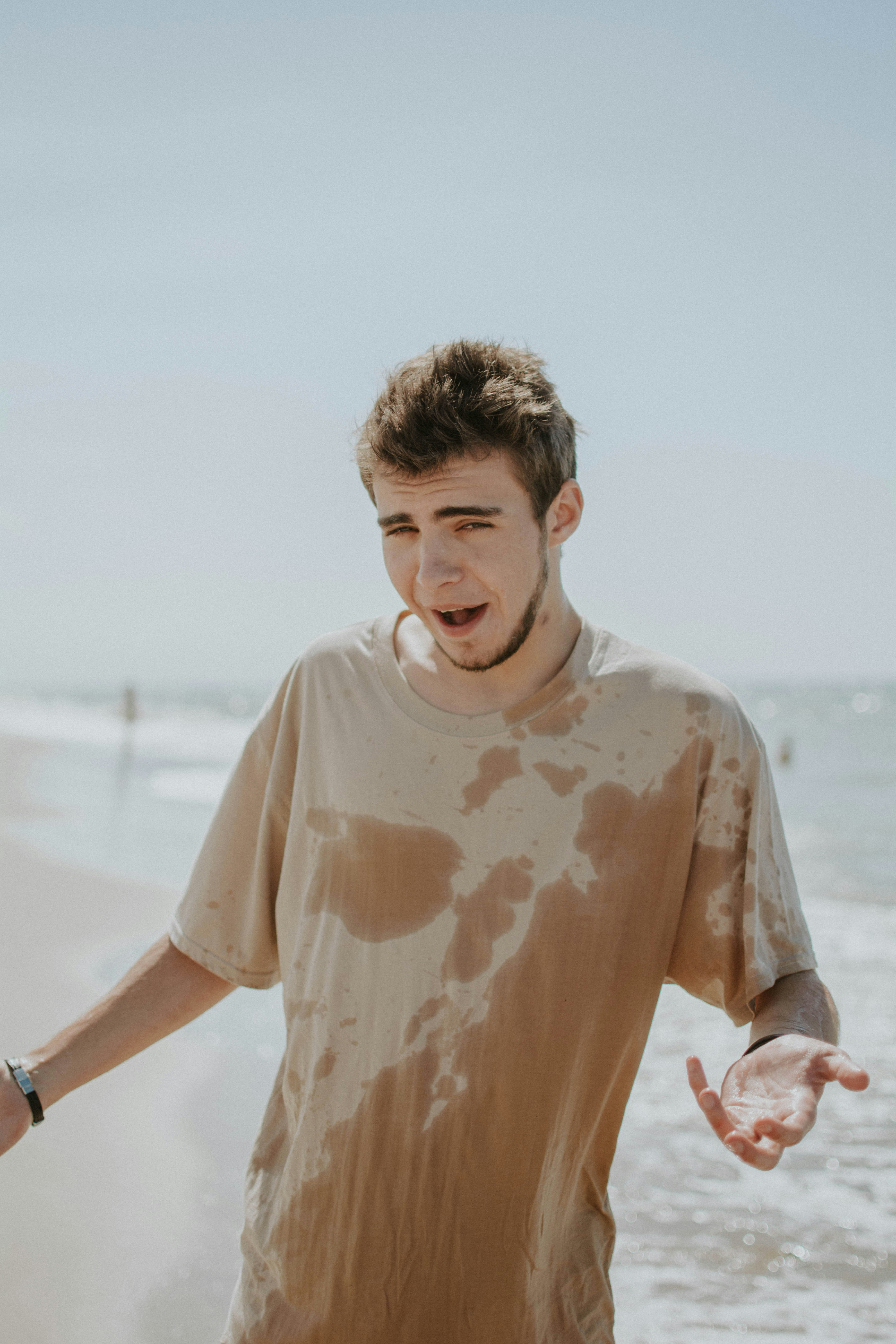 man in white crew neck t-shirt standing on beach during daytime