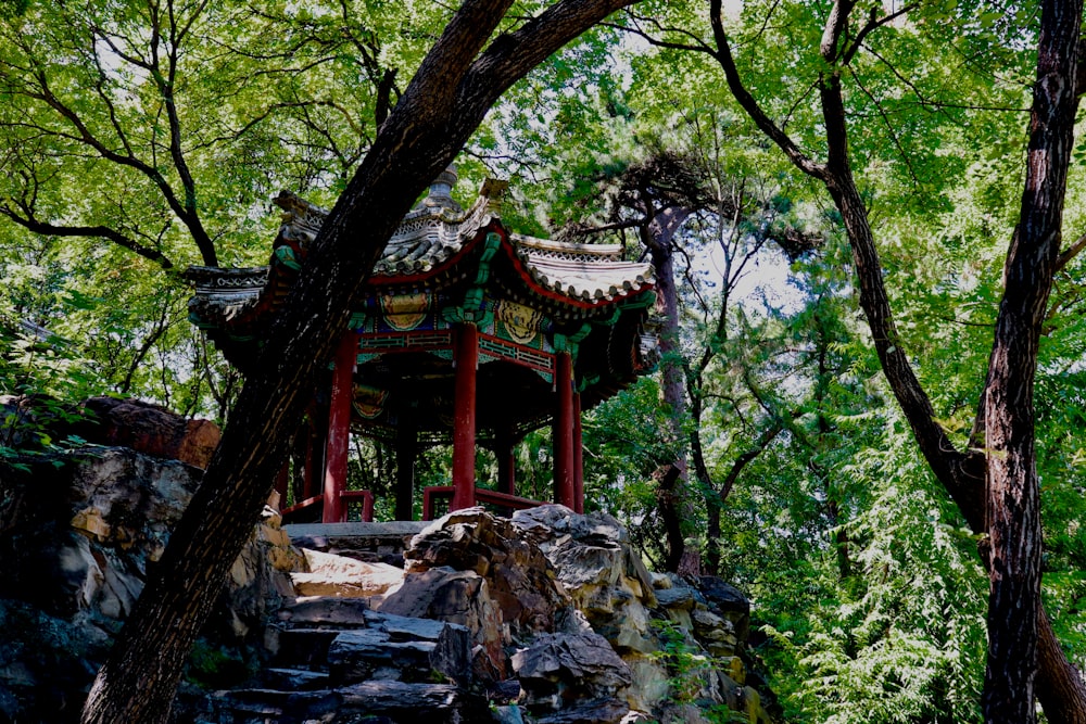 Temple en bois rouge et brun entouré d’arbres verts pendant la journée