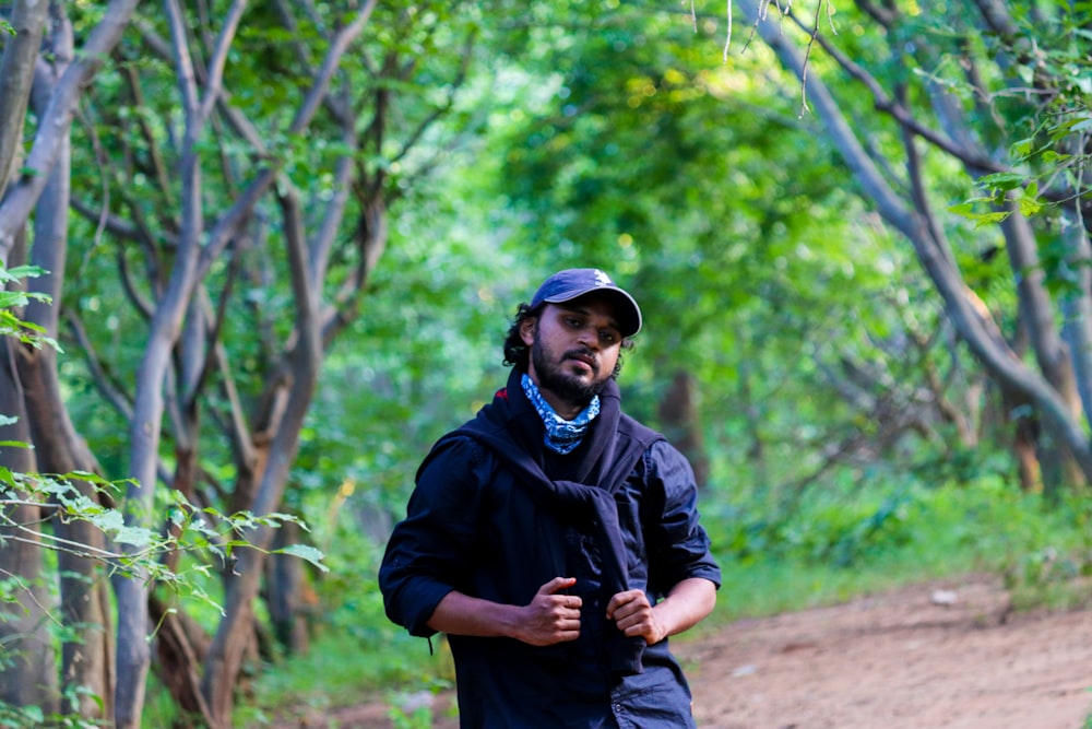 man in black jacket and black pants standing on forest during daytime