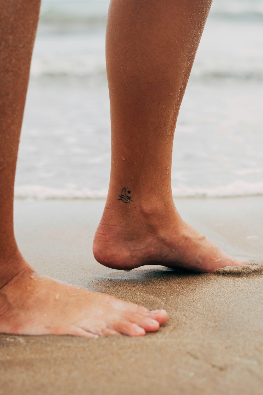 piedi di persone su sabbia bianca durante il giorno