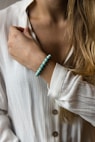 woman in white long sleeve shirt wearing silver and green beaded bracelet