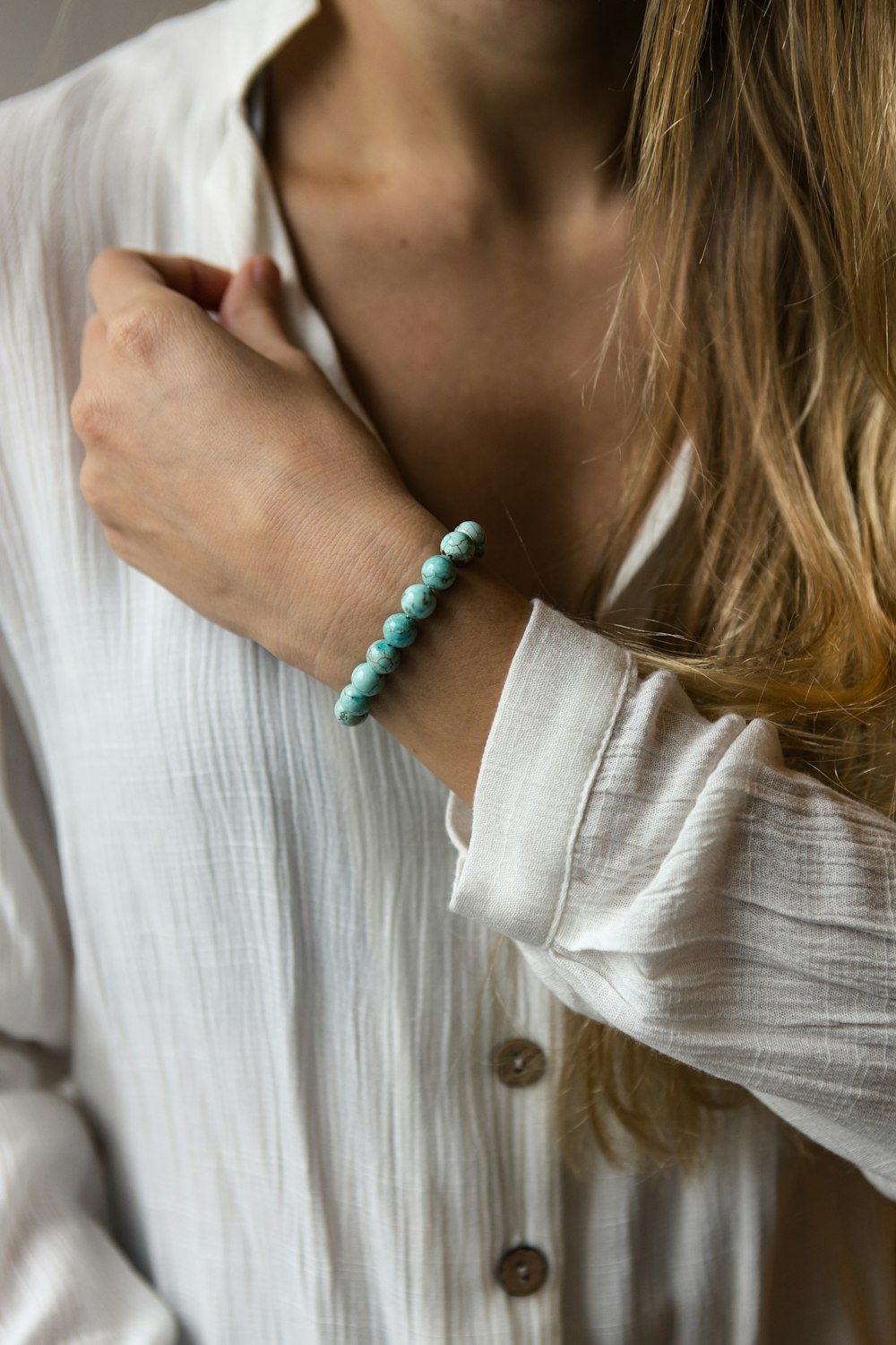 woman in white long sleeve shirt wearing silver and green beaded bracelet