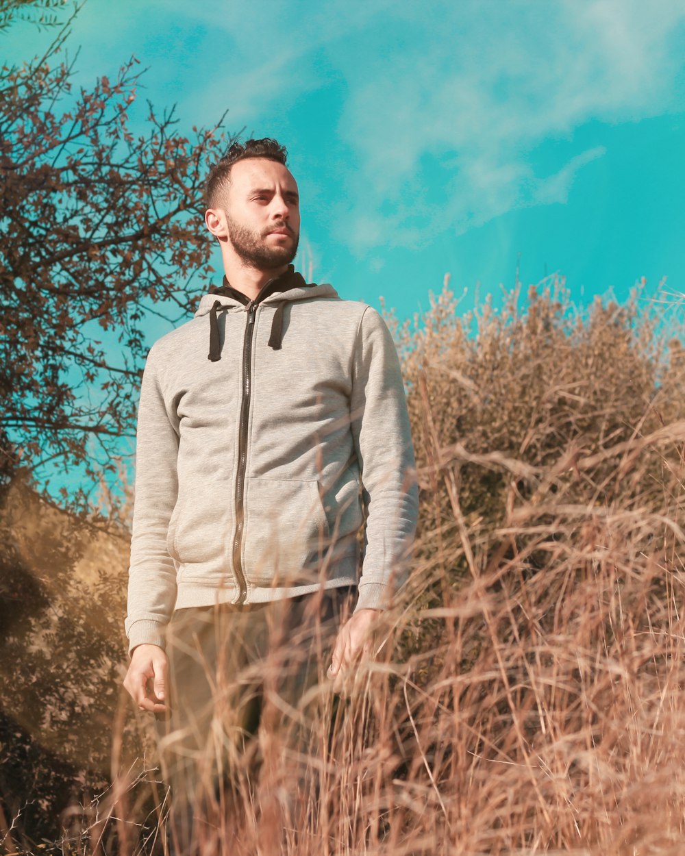 man in gray zip up jacket standing on brown grass field during daytime