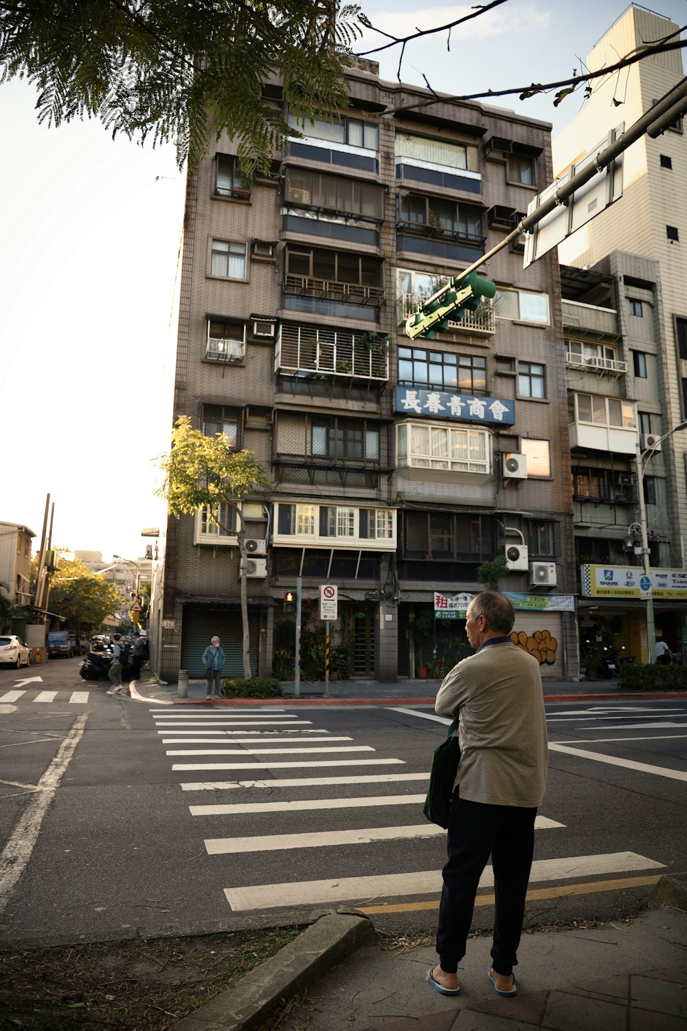 man in white long sleeve shirt walking on pedestrian lane during daytime