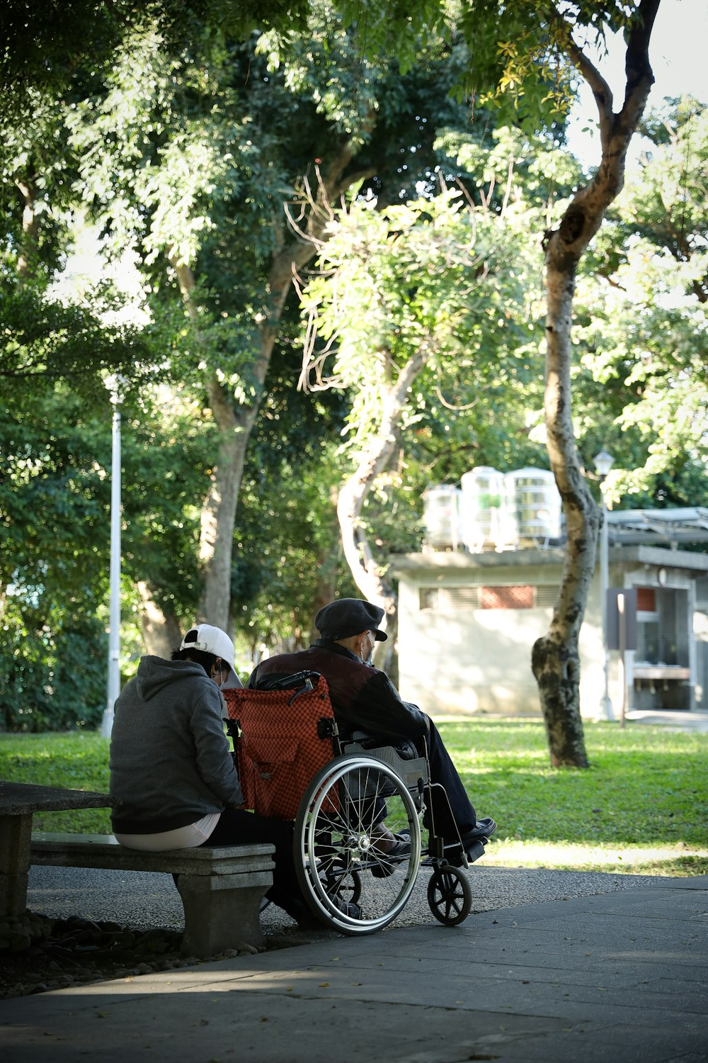 man in black jacket sitting on brown wooden bench during daytime