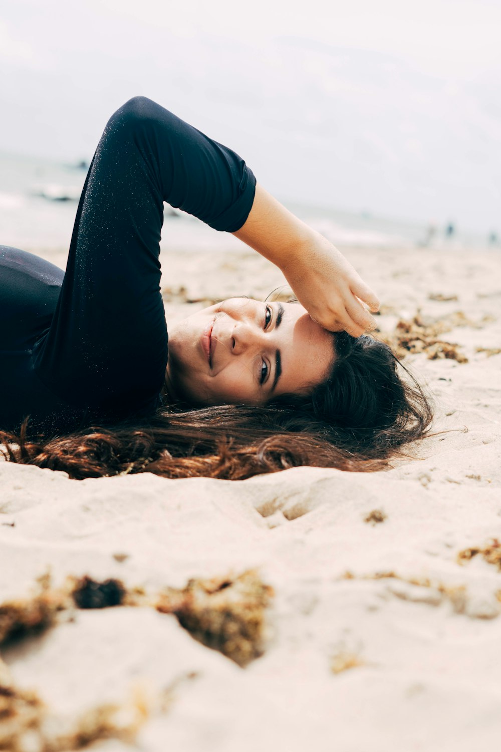 woman in blue shirt lying on sand during daytime