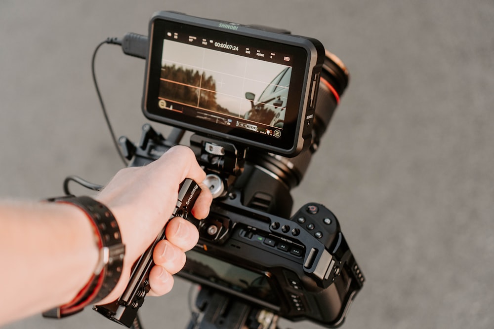 pessoa segurando câmera dslr preta