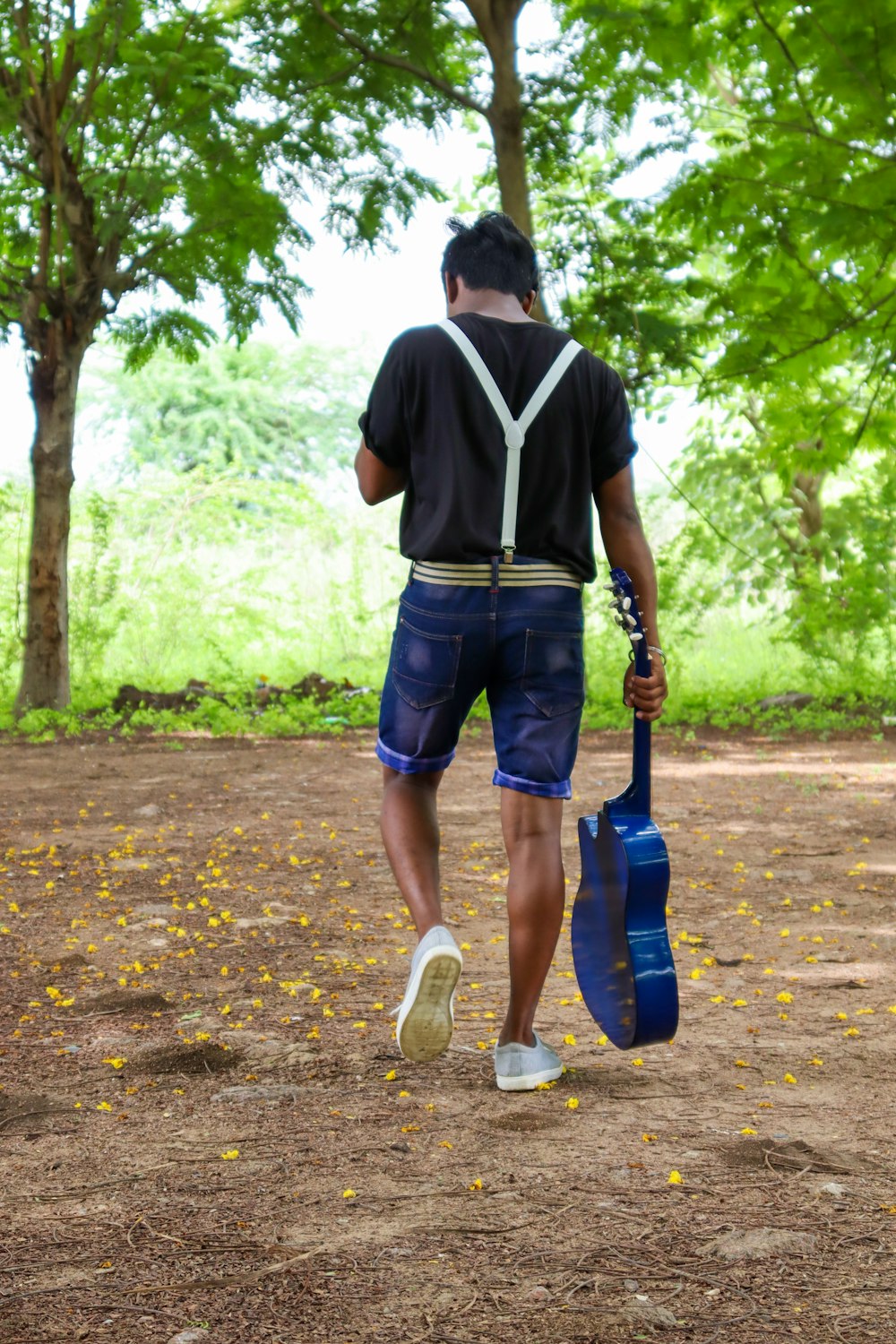 man in white and black v neck t-shirt and blue denim shorts holding black and