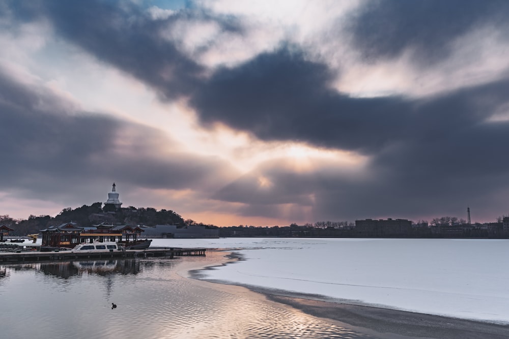 body of water near city under cloudy sky during daytime