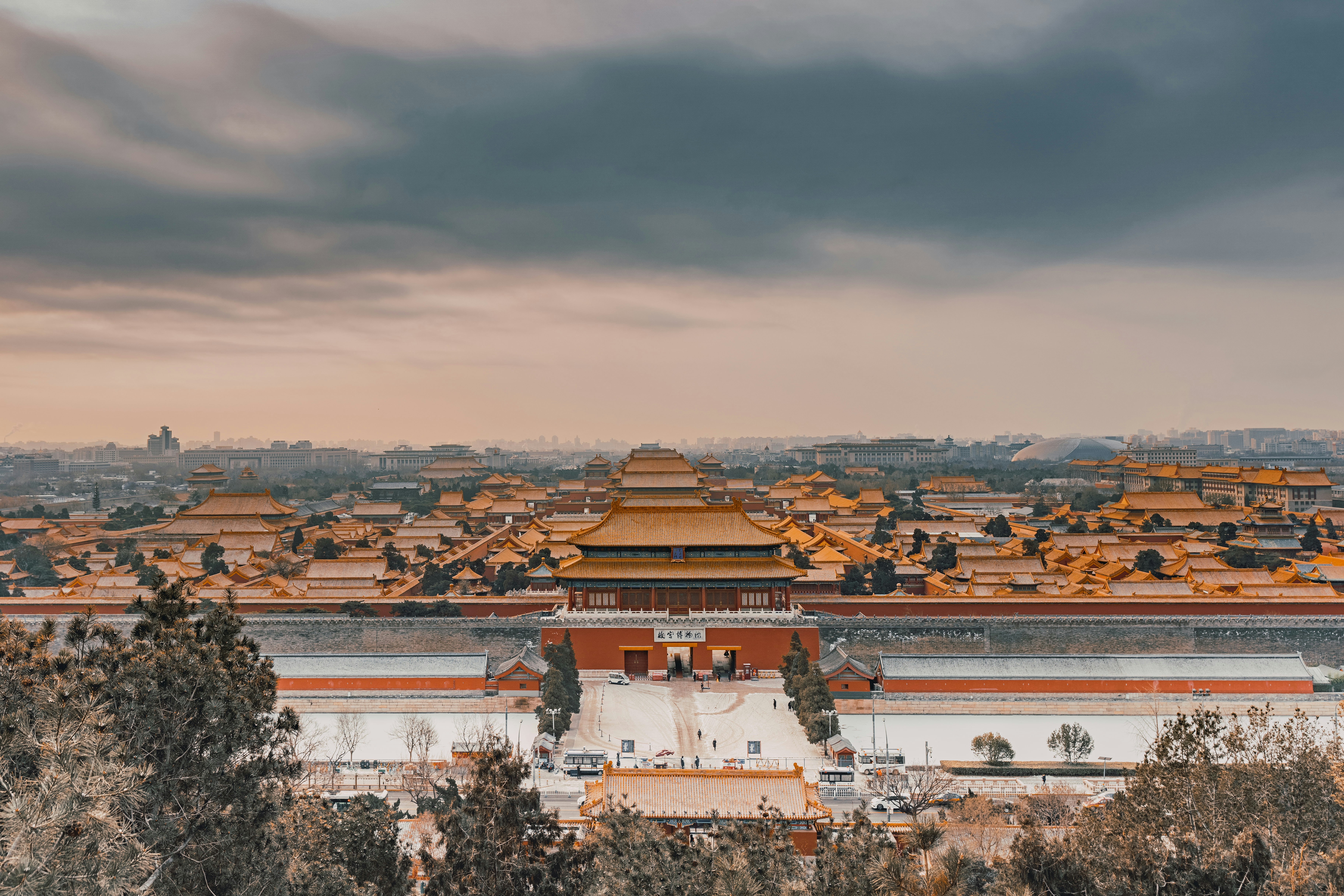 Wide view of the Forbidden City at sunrise with layered palace rooftops in warm light.