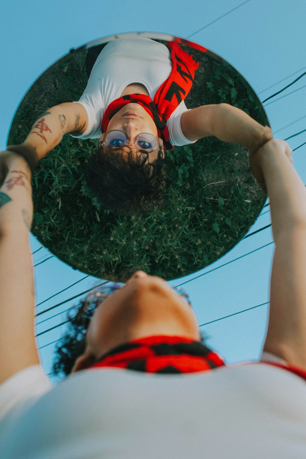 girl in white t-shirt lying on green round hole during daytime