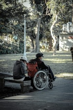 man in black jacket sitting on brown wooden bench during daytime