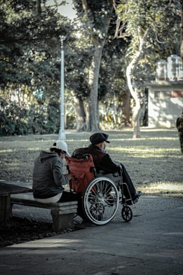 man in black jacket sitting on brown wooden bench during daytime