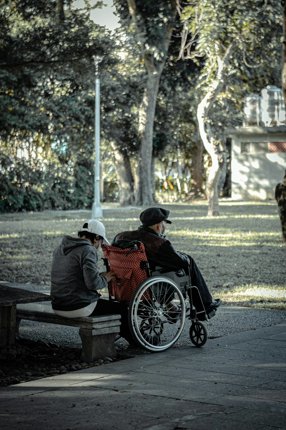 man in black jacket sitting on brown wooden bench during daytime