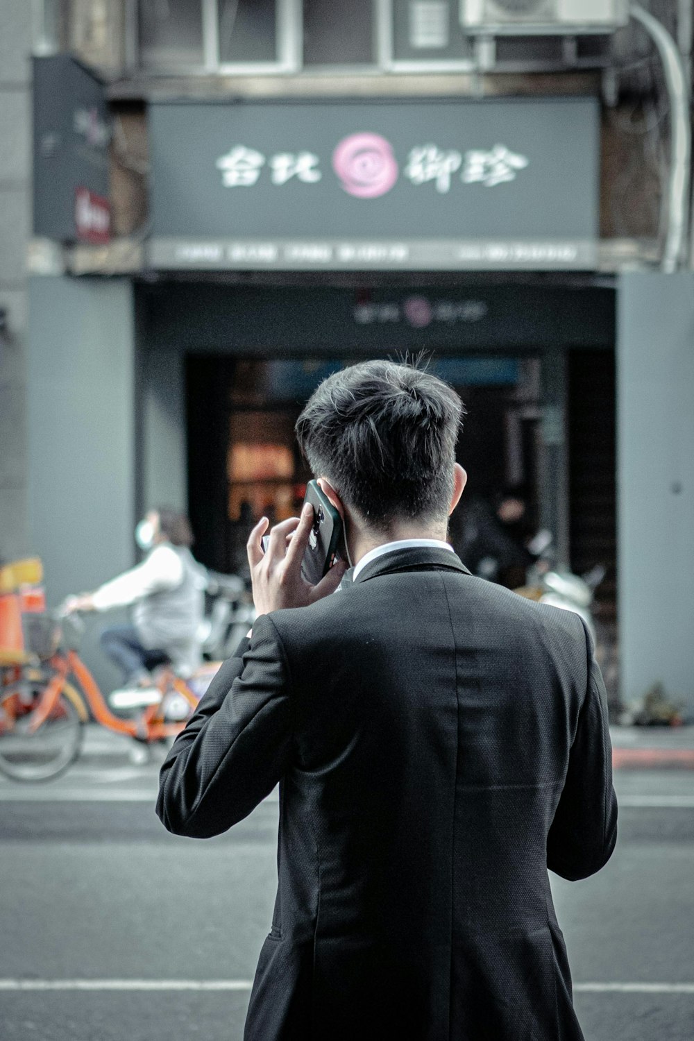 man in black suit jacket holding smartphone