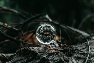 A softly glowing crystal ball resting on ancient wooden table, surrounded by flickering candles.