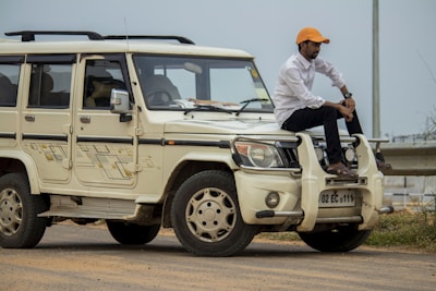 man in white long sleeve shirt and orange hat standing beside white jeep wrangler