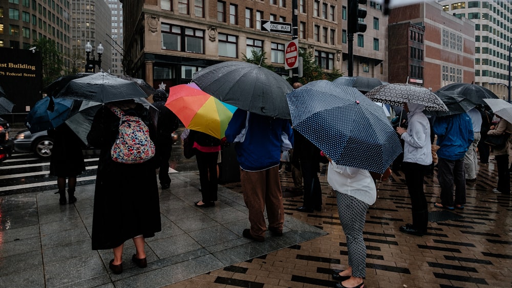 people walking on sidewalk with umbrella during daytime