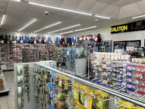 An outdoor supply store shelf stocked with colorful lures and tackle boxes.