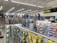 A well-lit store interior filled with fishing and outdoor equipment. The shelves are stocked with various lures, fishing lines, and other accessories. A range of colorful life vests is displayed on the back wall. A caution sign and a digital temperature display are mounted near the ceiling.