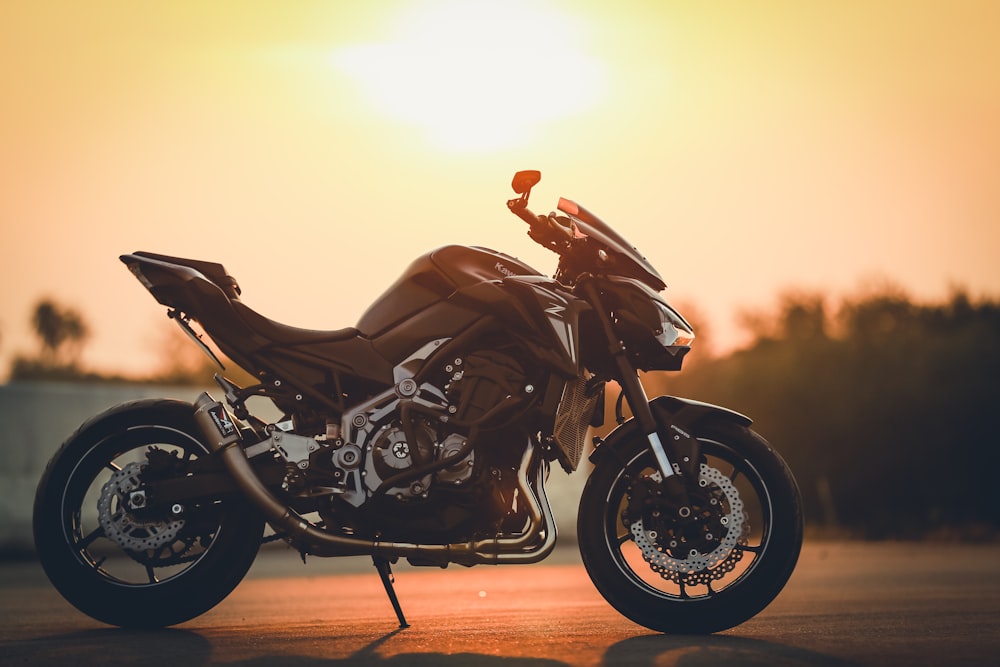 black sports bike on brown sand during sunset