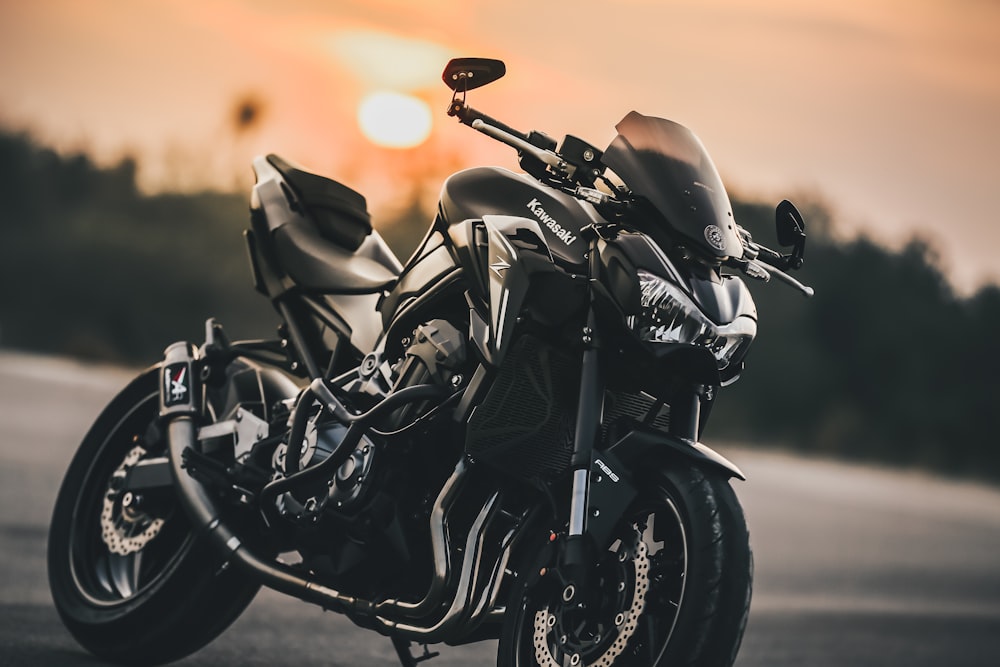 Schwarz-graues Motorrad auf grauer Asphaltstraße bei Sonnenuntergang