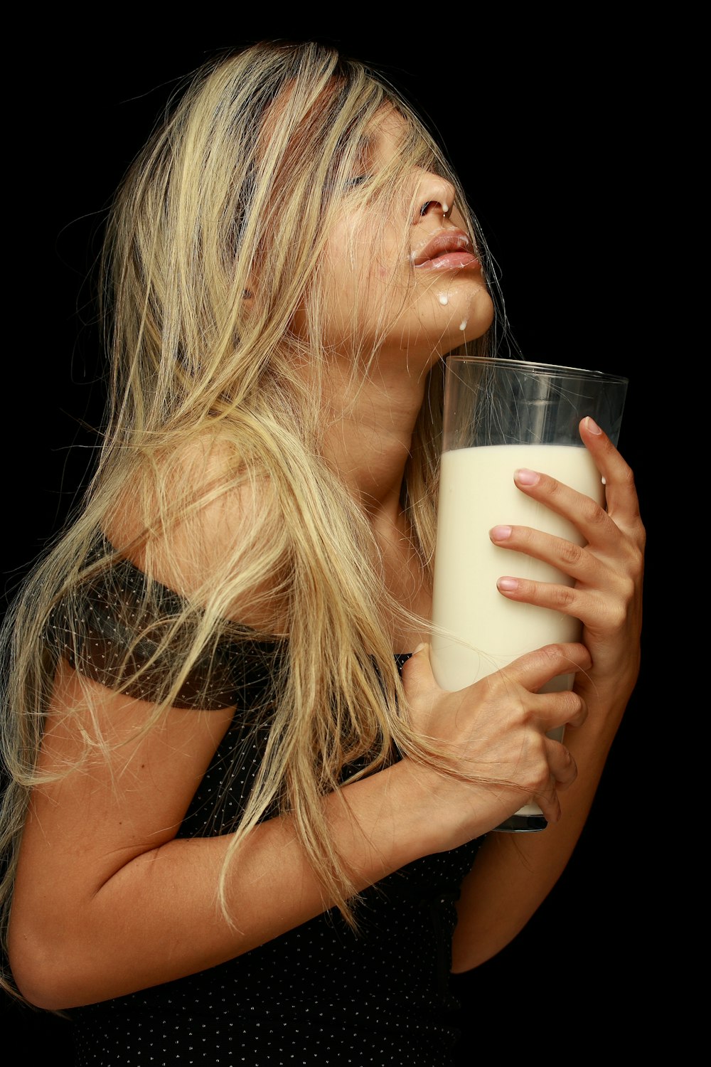 mujer sosteniendo un vaso transparente con líquido blanco