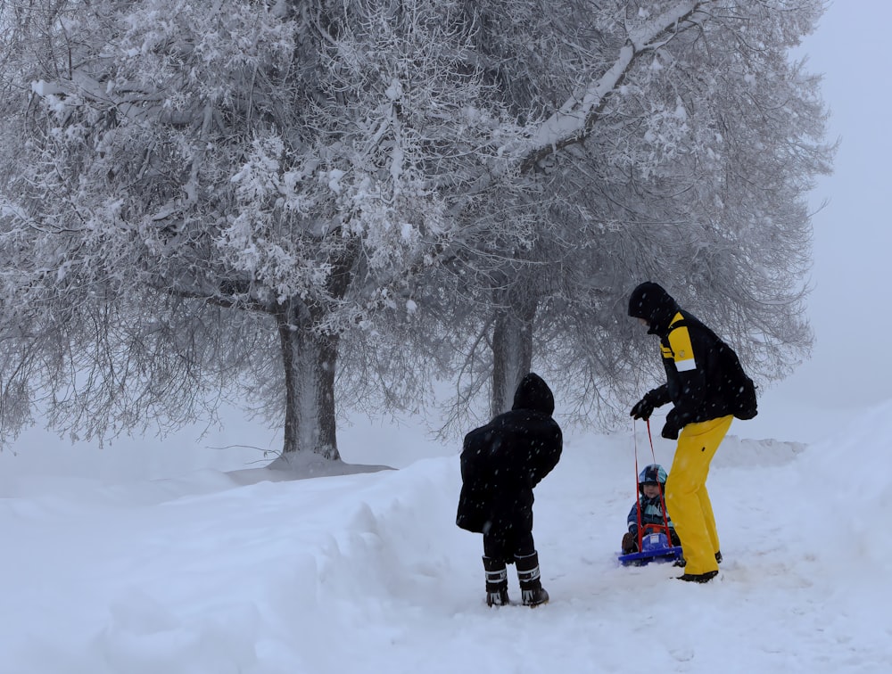 man in black jacket and yellow pants standing on snow covered ground during daytime