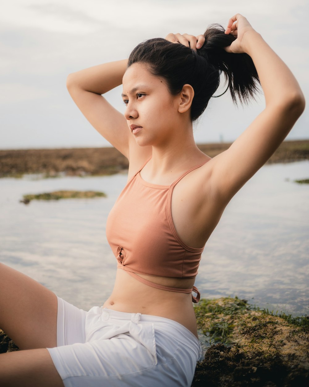 woman in white crop top and white shorts standing on green grass field during daytime