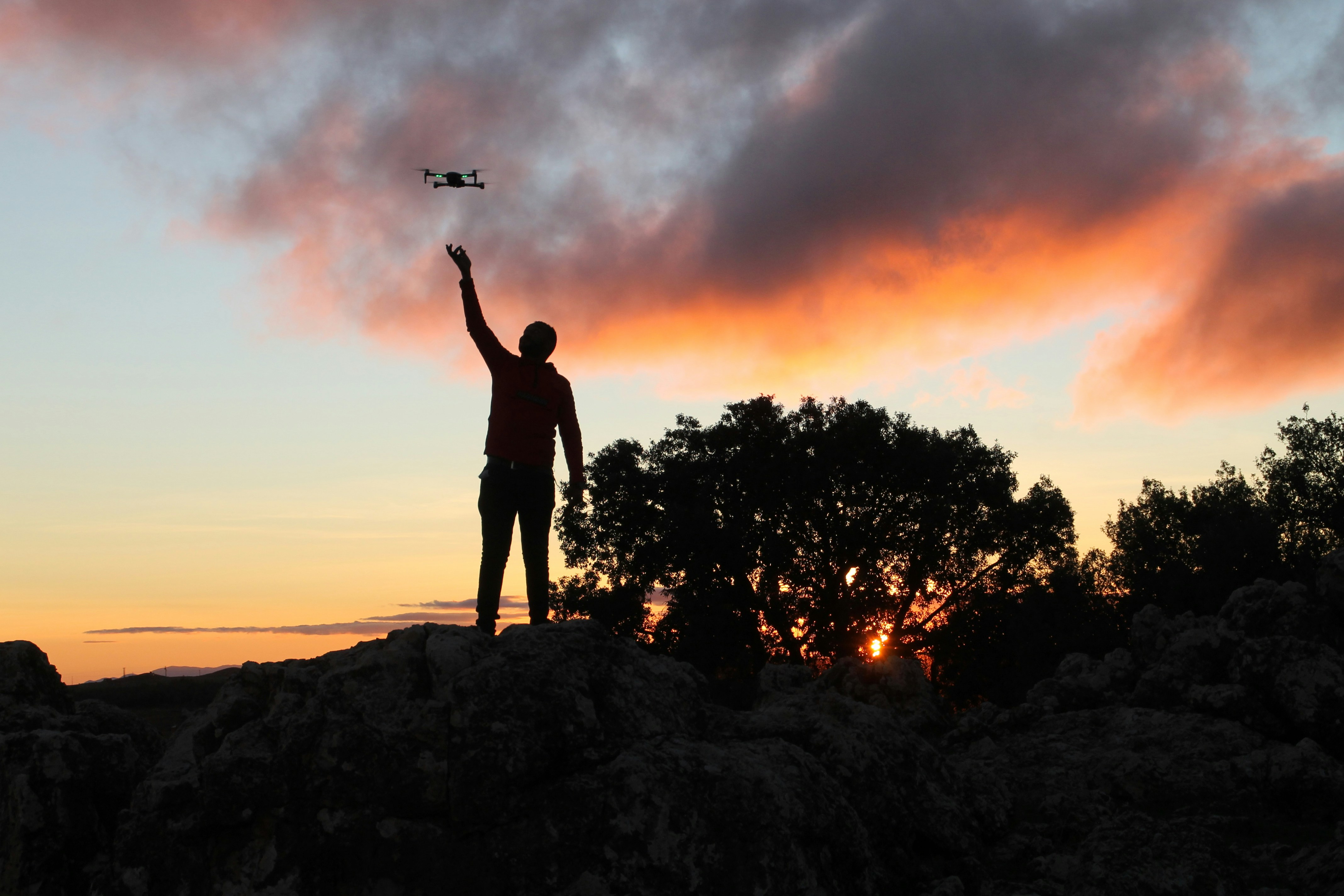 silhouette of man standing on rock during sunset