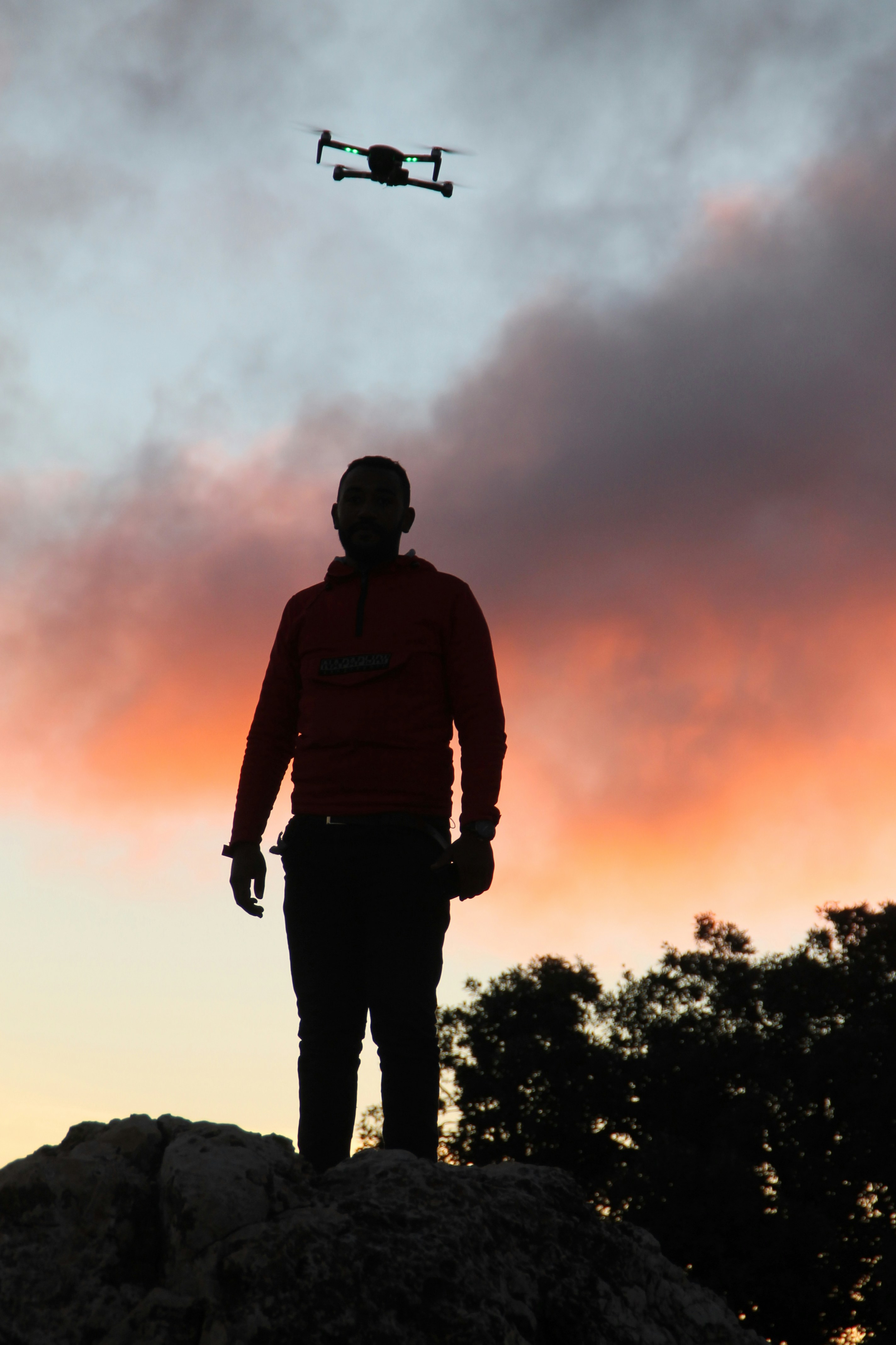 man in black and red hoodie standing on the ground during sunset