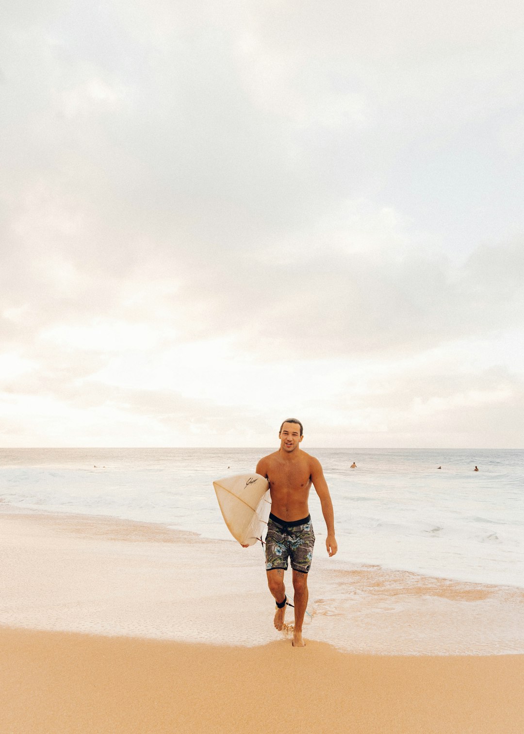 man in black shorts holding white surfboard standing on beach during daytime