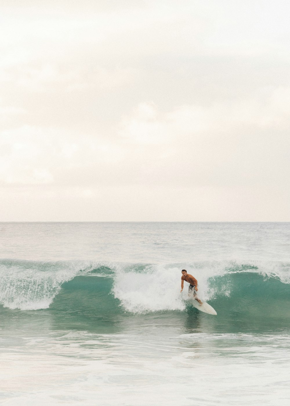 woman in white bikini surfing on sea waves during daytime