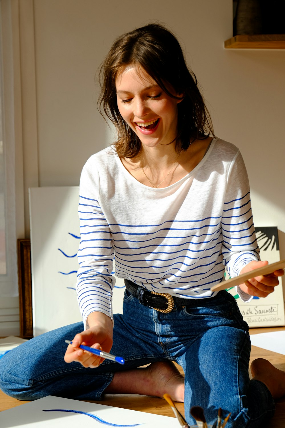woman in white and black striped long sleeve shirt and blue denim jeans  sitting on brown photo – Free Image on Unsplash