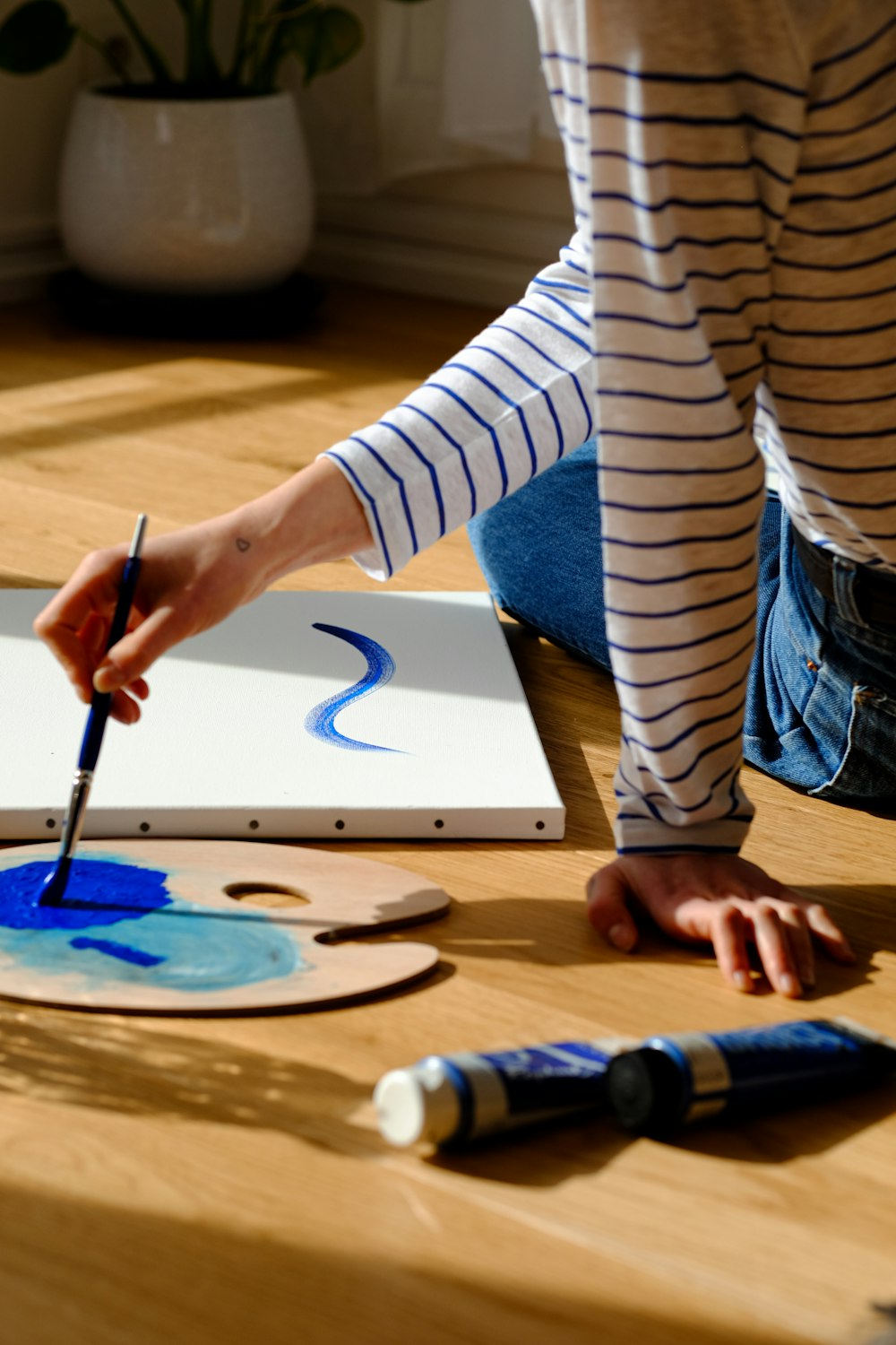 person in white and blue striped long sleeve shirt painting on white paper